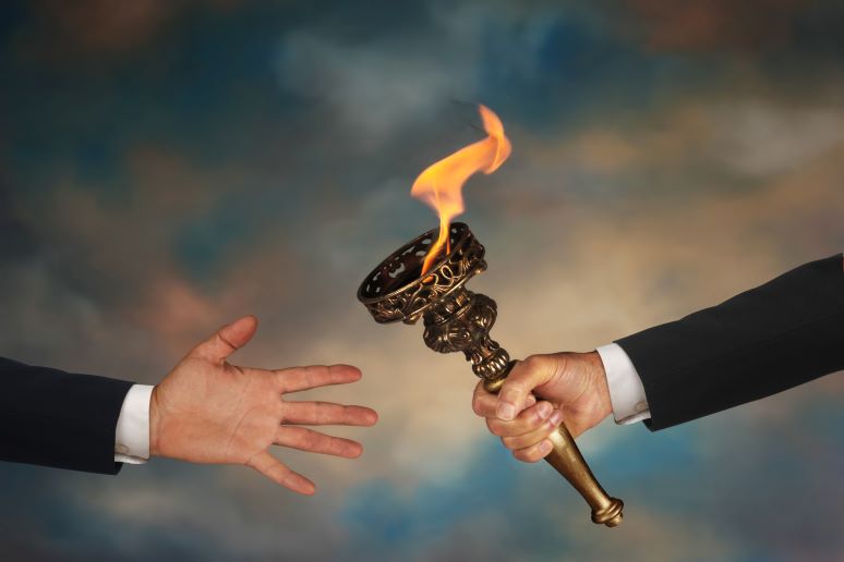 Photo showing hand off of torch from one CEO to the next