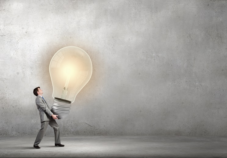 Photo illustration of a man carrying an oversized lightbulb