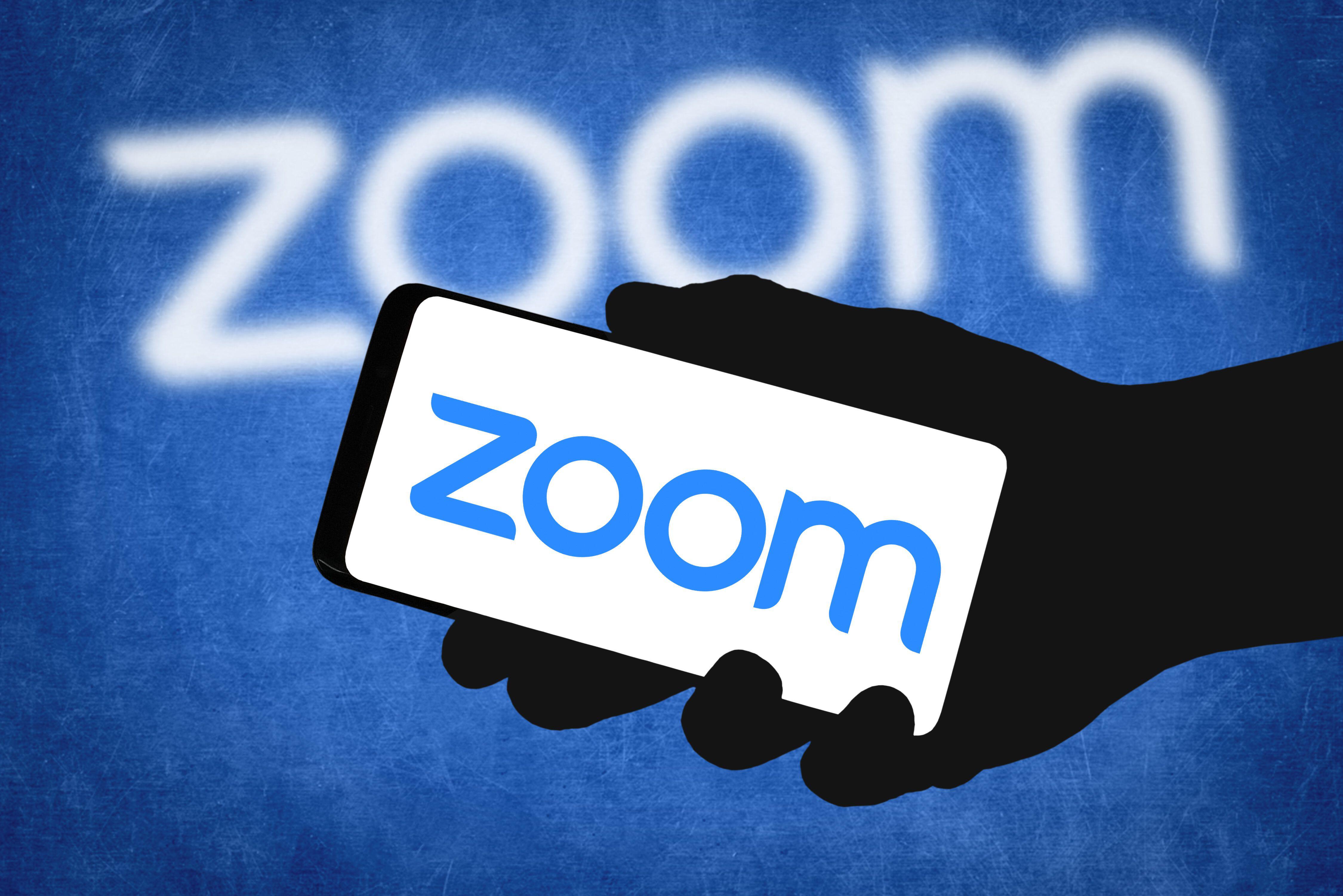 hand-holding-zoom-logo-in-front-of-zoom-screen.jpg