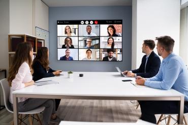 Photo showing virtual meeting with some people in office others remote