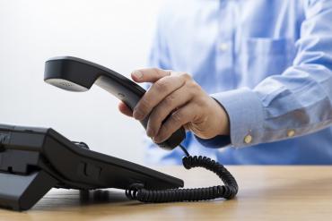 Businessman picking up deskphone to place call