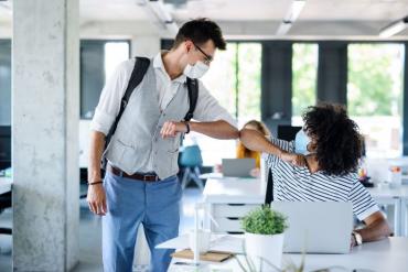 Young professionals elbow-bumping as they return to the office