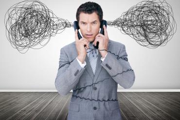 A man is listening to two separate phones and he has a cloud of confusion over his head