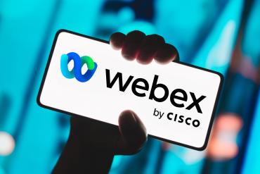 A hand holds a mobile phone bearing the Webex by Cisco label